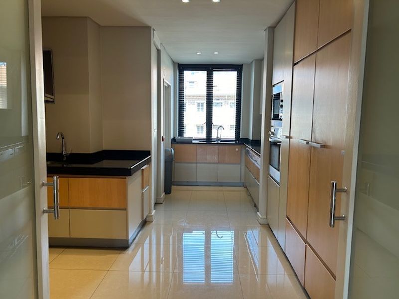A modern, well-maintained kitchen featuring light wood cabinetry, granite countertops, integrated appliances, and polished tile flooring in a clean, open layout.