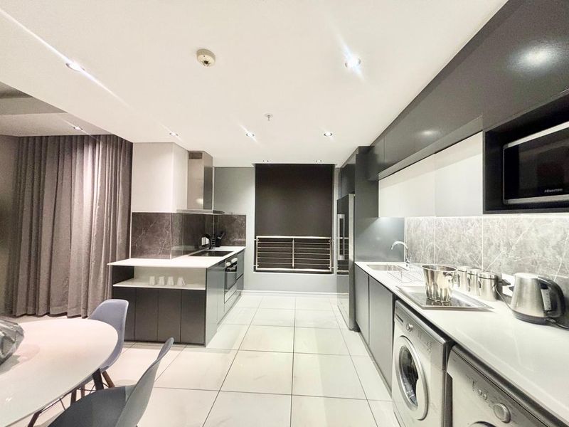 Modern kitchen featuring sleek dark cabinetry, stone countertops, integrated appliances, recessed lighting, and tiled flooring in a clean, contemporary layout.