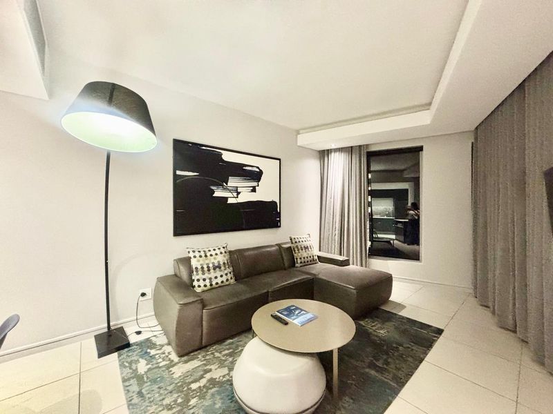 A modern living room featuring tiled flooring, a recessed ceiling design, and large windows with integrated curtain tracks.