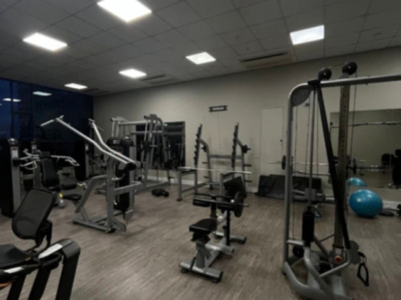 A functional apartment gym facility featuring laminate flooring, recessed lighting, and wall-mounted mirrors.