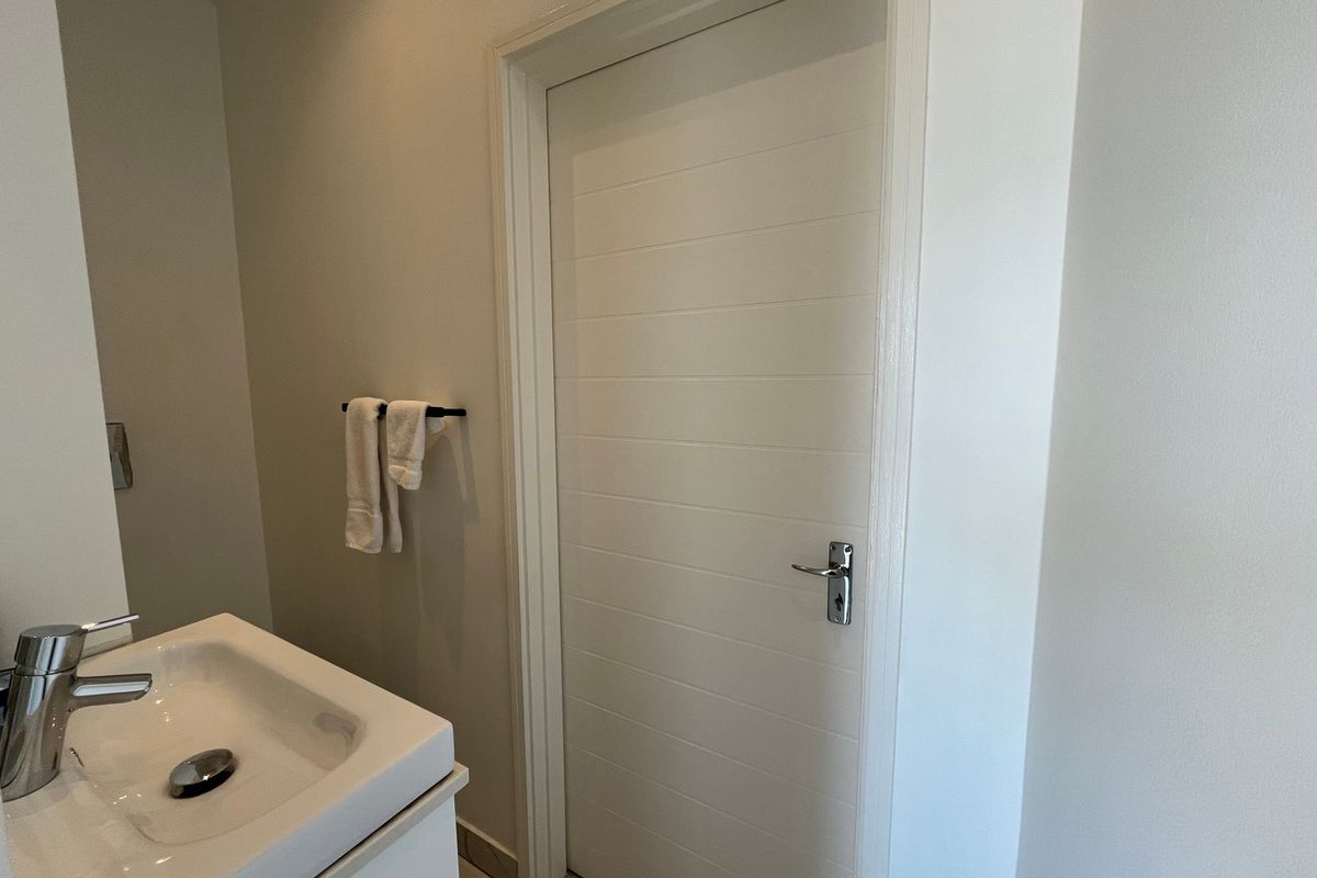A clean and functional bathroom featuring a modern vanity basin with a chrome mixer tap and a white internal door.