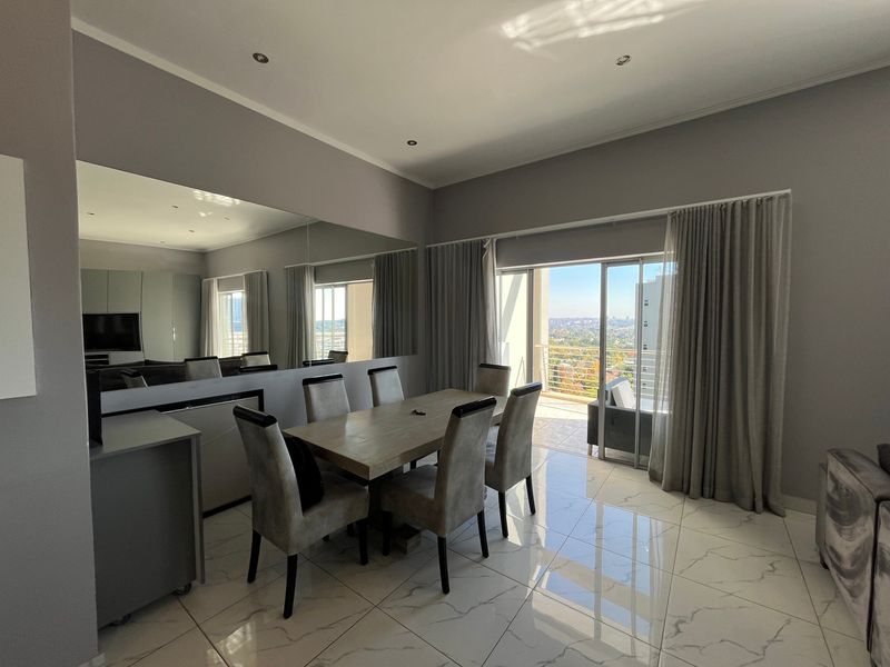 Modern dining area featuring polished porcelain floor tiles, recessed lighting, a large feature mirror, and direct access to a balcony with city views.