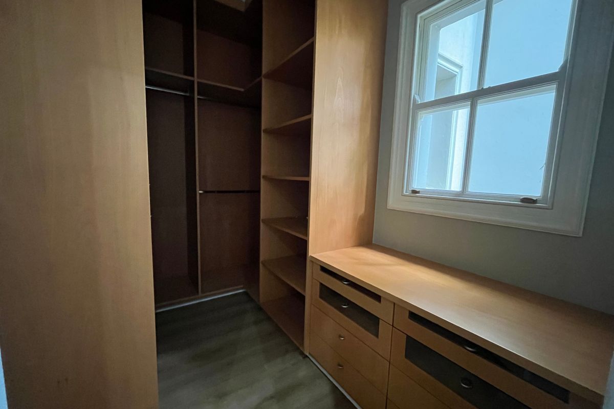A walk-in closet or dressing area featuring extensive built-in wooden cabinetry, shelving, and drawers with a window for natural light.