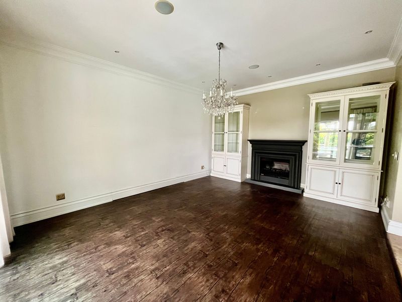 Spacious living room featuring dark hardwood flooring, built-in display cabinetry, a classic fireplace, and elegant crown molding.