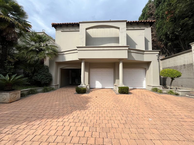 Front elevation of a cluster home featuring a paved driveway, double garage, and an upper-level balcony with architectural columns.