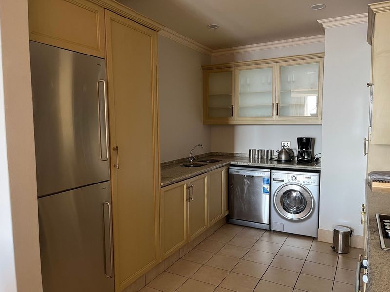 A functional kitchen featuring built-in cabinetry, granite countertops, integrated dishwasher, and a built-in washing machine, offering a practical layout for daily tasks.
