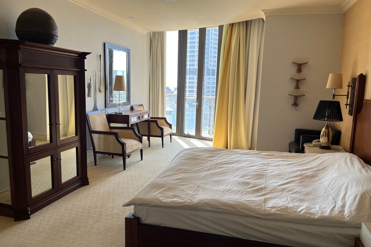 Spacious bedroom featuring neutral carpeting, crown molding, recessed lighting, and a large glass door providing access to a private balcony with city views.