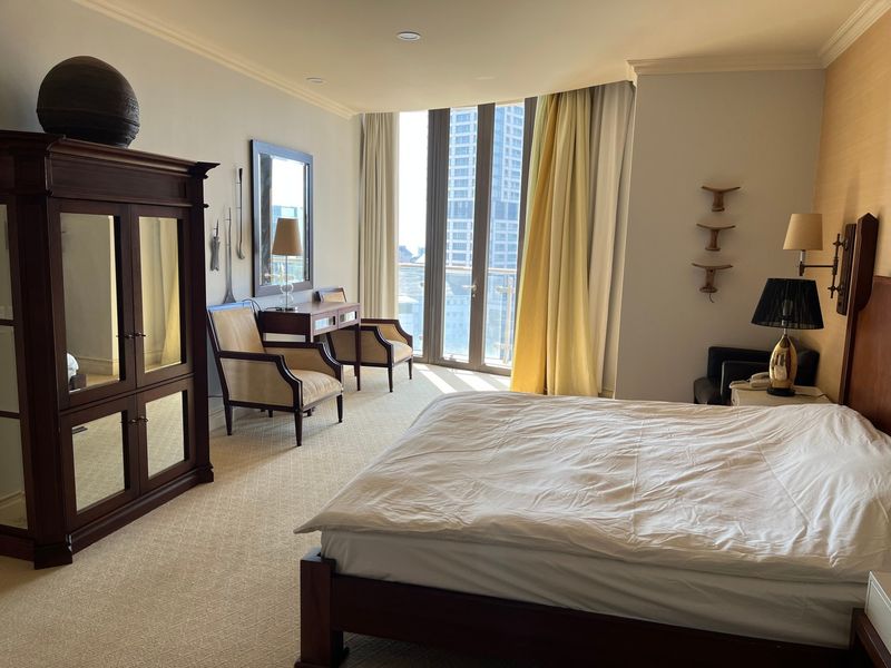 Spacious bedroom featuring neutral carpeting, crown molding, recessed lighting, and a large glass door providing access to a private balcony with city views.