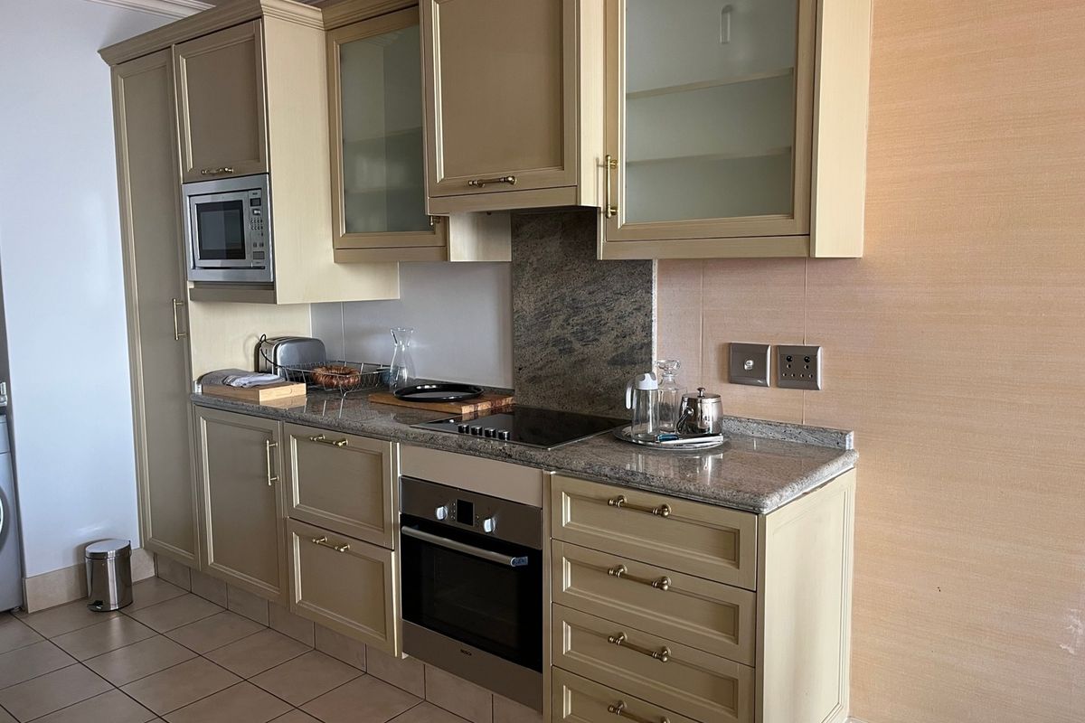 A functional kitchen featuring light-toned cabinetry, granite countertops, integrated oven, electric cooktop, and built-in microwave with tiled flooring.