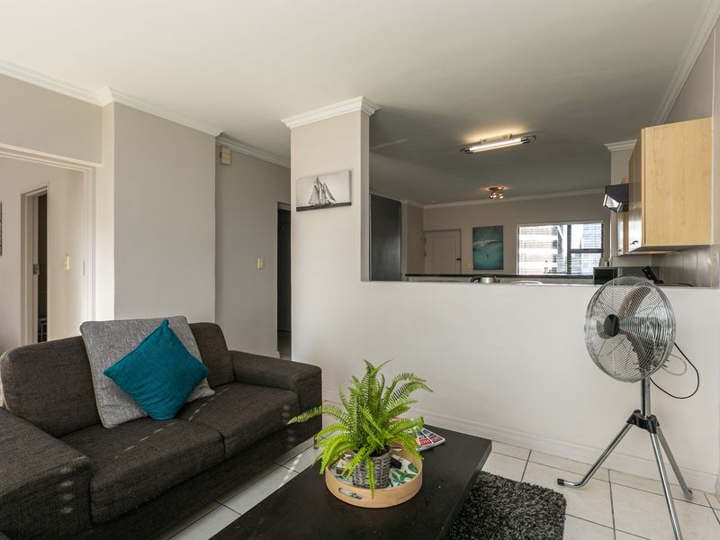 Open-plan living area featuring tiled flooring and a pass-through window connecting to the kitchen space.
