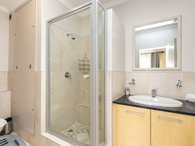 A functional bathroom featuring a glass-enclosed shower, a vanity with a granite countertop, and a wall-mounted mirror.