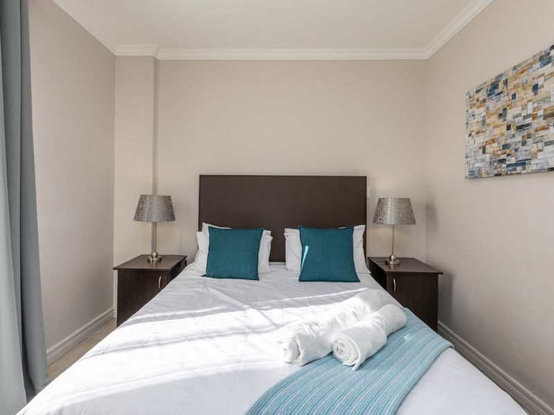 A well-maintained bedroom featuring neutral wall tones, crown molding, and baseboards, providing a clean and comfortable sleeping space.