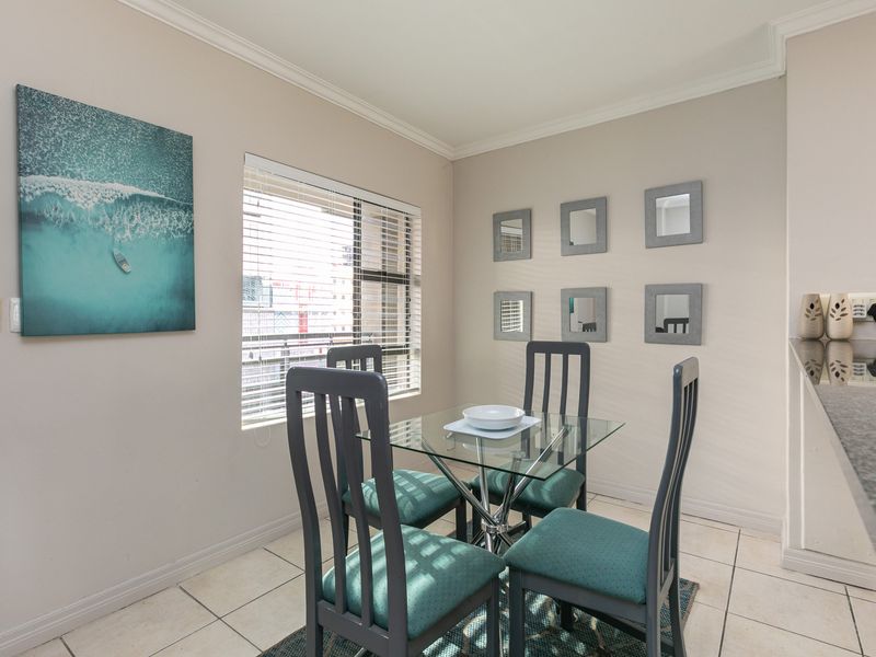 A bright dining area featuring tiled flooring, coving, and a window with venetian blinds, adjacent to a granite-topped breakfast bar.