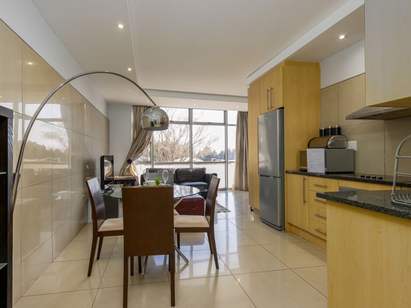 Modern open-plan living area featuring a sleek kitchen with granite countertops, tiled flooring, and large glass doors leading to an outdoor space.