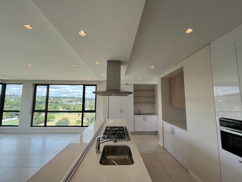 Modern open-plan kitchen featuring a central island with gas hob, integrated appliances, sleek cabinetry, and expansive windows offering panoramic views.