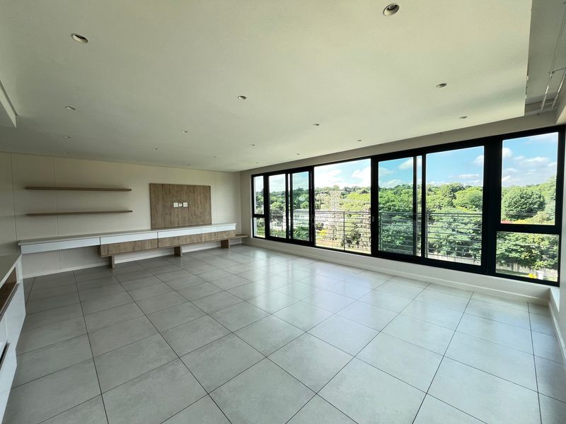 Spacious, modern living area featuring large format floor tiles, built-in media cabinetry, floating shelves, and expansive sliding glass doors with natural light.
