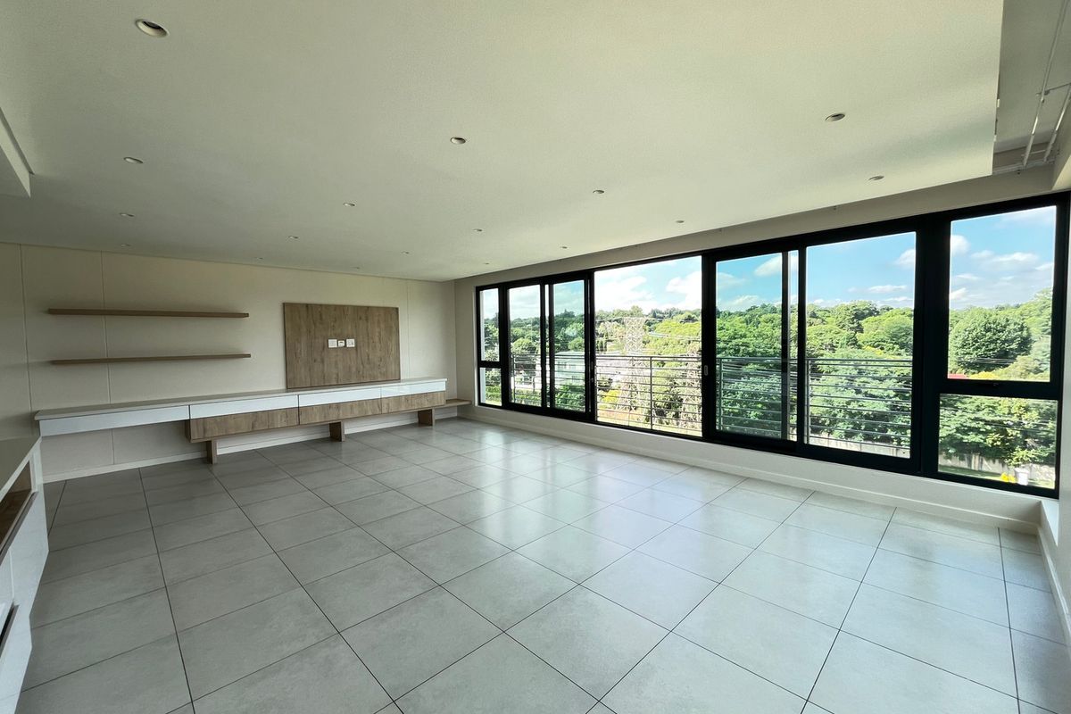 Spacious, modern living area featuring large format floor tiles, built-in media cabinetry, floating shelves, and expansive sliding glass doors with natural light.