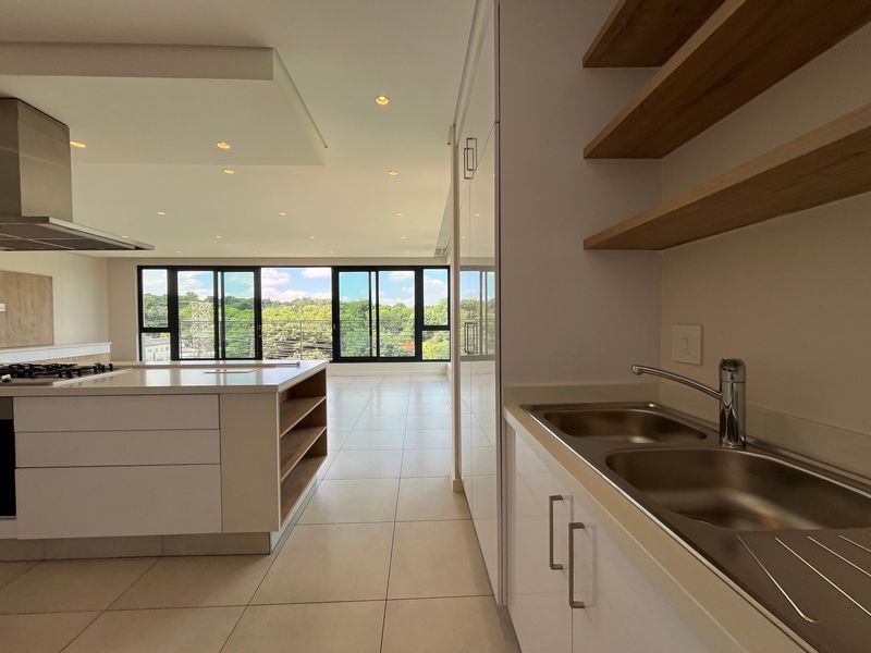 Modern open-plan kitchen and living area featuring a central island, sleek cabinetry, high-end finishes, and large sliding doors with expansive views.