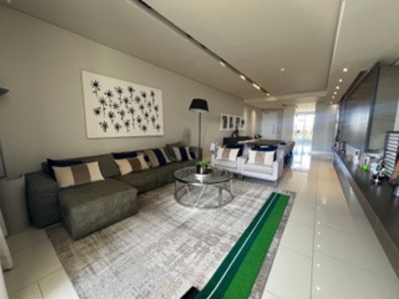 A spacious open-plan living area featuring modern tiled flooring, recessed ceiling lighting, and sleek built-in cabinetry, creating a contemporary and cohesive living space.