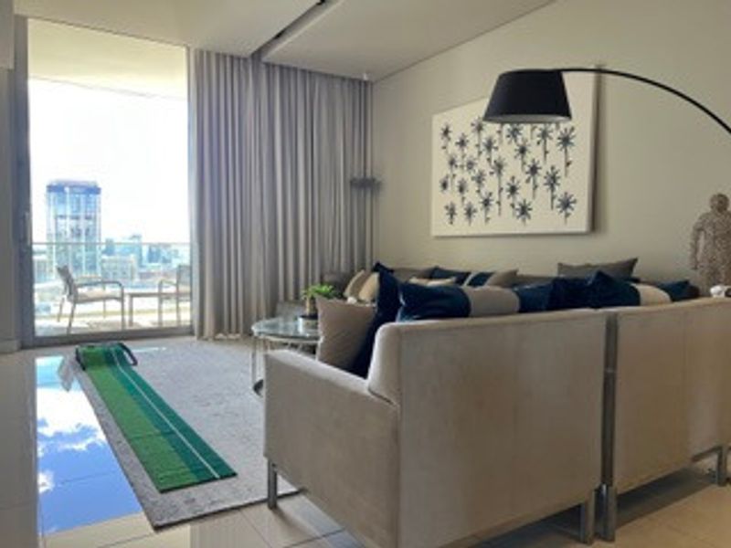 Modern living room featuring large sliding glass doors leading to a balcony, neutral tiled flooring, and recessed ceiling lighting.