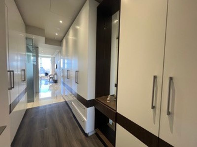 A modern hallway featuring extensive built-in cabinetry with a sleek two-tone finish and a dedicated vanity or display nook.
