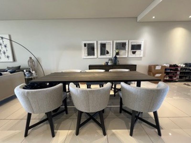 A well-lit dining area featuring modern recessed downlighting and neutral tiled flooring, providing a clean and functional space for meals.