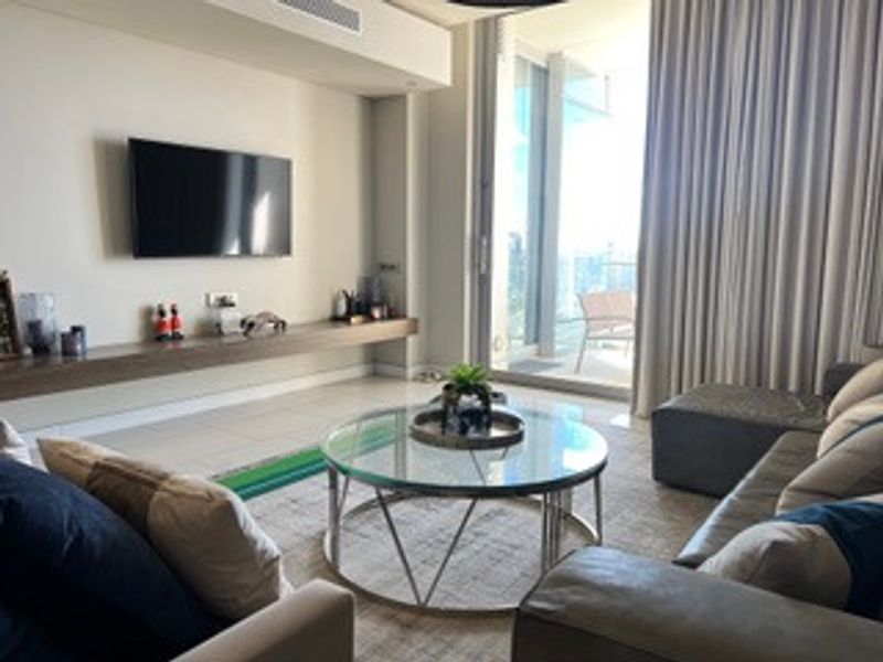 Modern living room featuring tiled flooring, a sleek floating media shelf, and large sliding glass doors providing access to an outdoor balcony area.