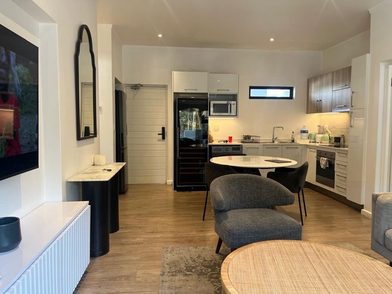Modern open-plan living area featuring a well-equipped kitchen with built-in cabinetry, integrated appliances, and sleek laminate flooring throughout.