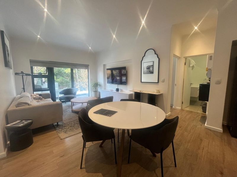 An open-plan living and dining area featuring modern laminate flooring, recessed lighting, and a sliding glass door leading to an outdoor space.