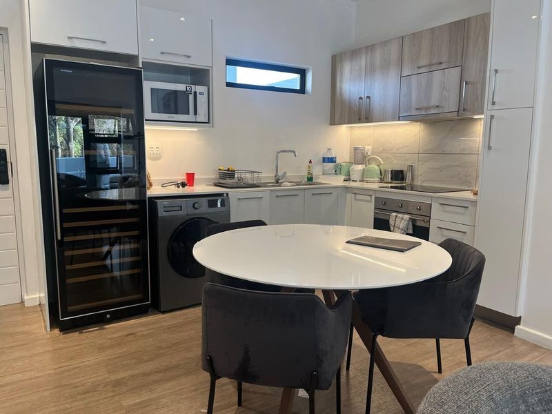 Modern kitchen featuring sleek cabinetry, integrated wine cooler, built-in oven, cooktop, and high-quality laminate flooring, offering a functional and contemporary cooking space.