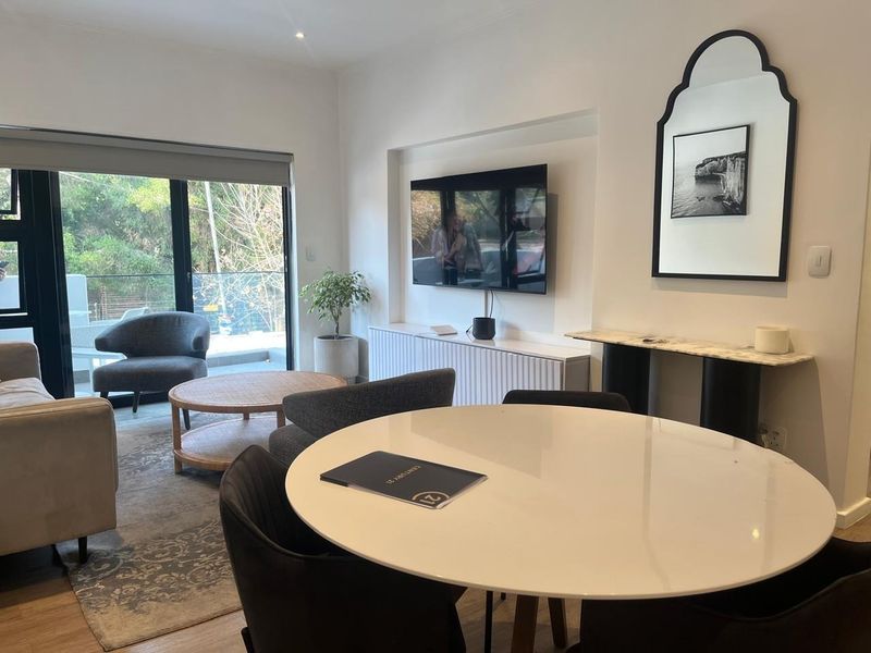 A bright and modern living area featuring laminate flooring, a recessed wall niche for media, and large sliding glass doors leading to an outdoor space.
