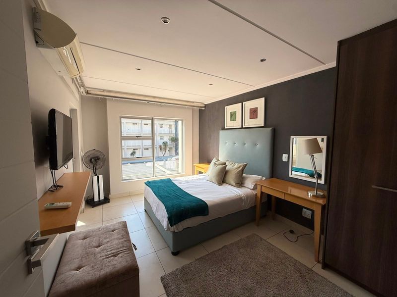 A well-maintained bedroom featuring tiled flooring, recessed lighting, an air conditioning unit, and a built-in wardrobe.