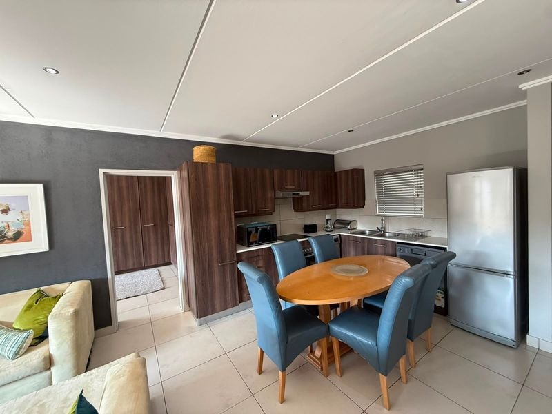 Open-plan kitchen and dining area featuring dark wood cabinetry, tiled flooring, and recessed lighting, seamlessly connected to the living space.