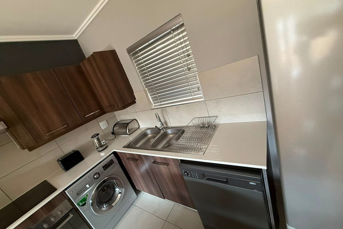 A functional kitchen featuring dark wood cabinetry, a double sink, tiled backsplash, and built-in appliances including an oven and hob.