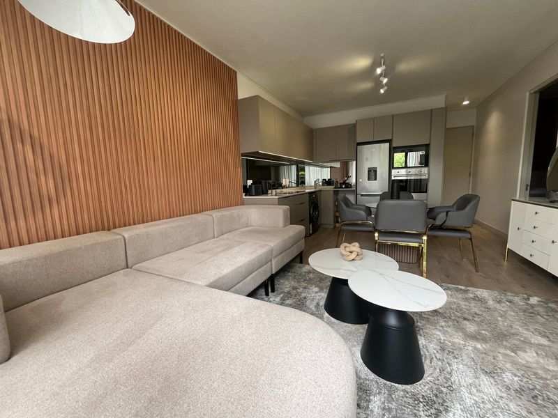 Modern open-plan living and dining area featuring a stylish slatted timber accent wall, contemporary kitchen cabinetry, and high-quality integrated appliances.