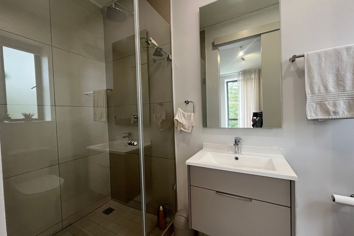 Modern bathroom featuring a walk-in shower with a glass screen, rain shower head, and a sleek wall-mounted vanity with an integrated basin.