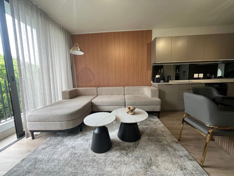 Modern open-plan living area featuring contemporary kitchen cabinetry, stylish slatted timber wall accents, and seamless access to a private balcony through sliding glass doors.