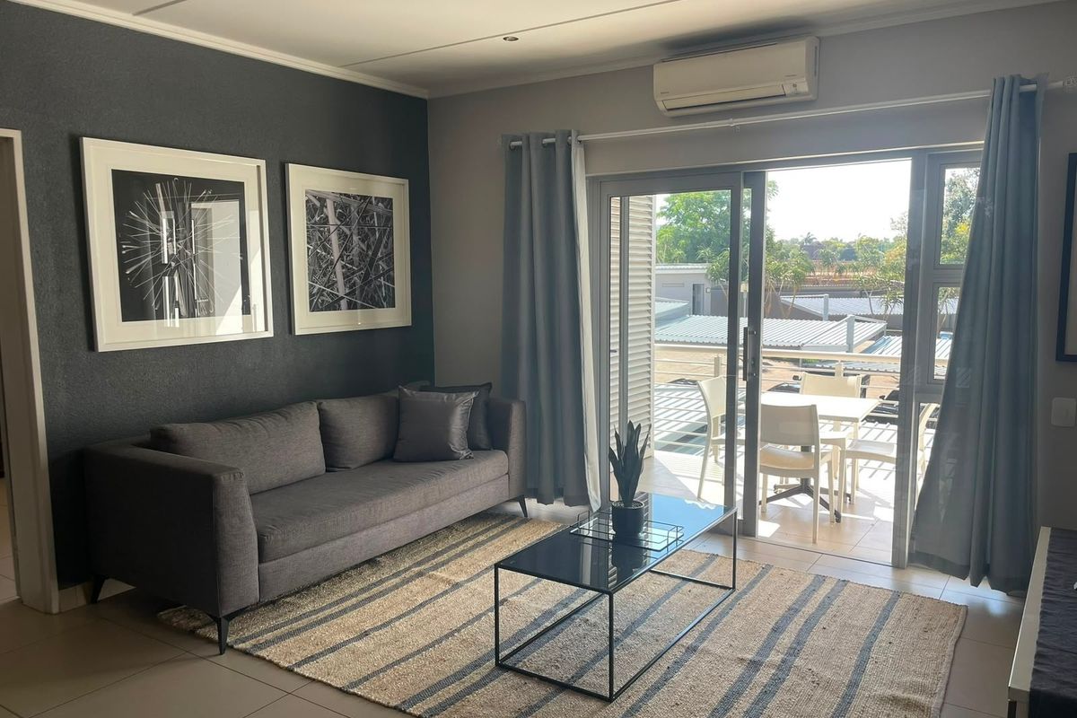 Modern living room featuring tiled floors, a wall-mounted air conditioning unit, and large sliding glass doors providing seamless access to an outdoor balcony area.