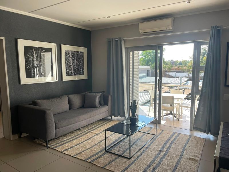 Modern living room featuring tiled floors, a wall-mounted air conditioning unit, and large sliding glass doors providing seamless access to an outdoor balcony area.