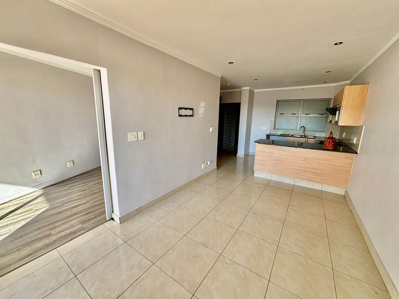 An open-plan living and kitchen area featuring tiled floors, modern cabinetry, and granite countertops, offering a clean and functional space.