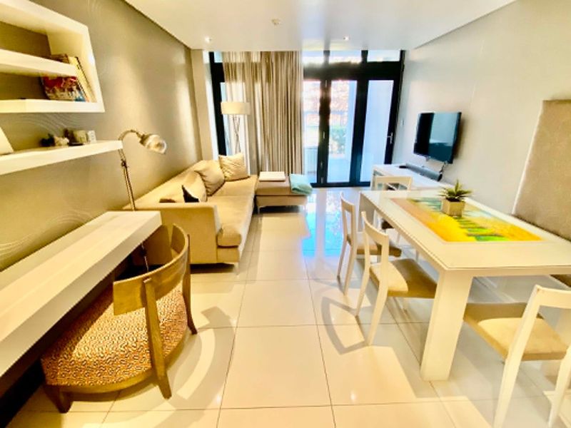 Modern open-plan living and dining area featuring polished tiled floors, recessed lighting, and large sliding glass doors leading to an outdoor space.