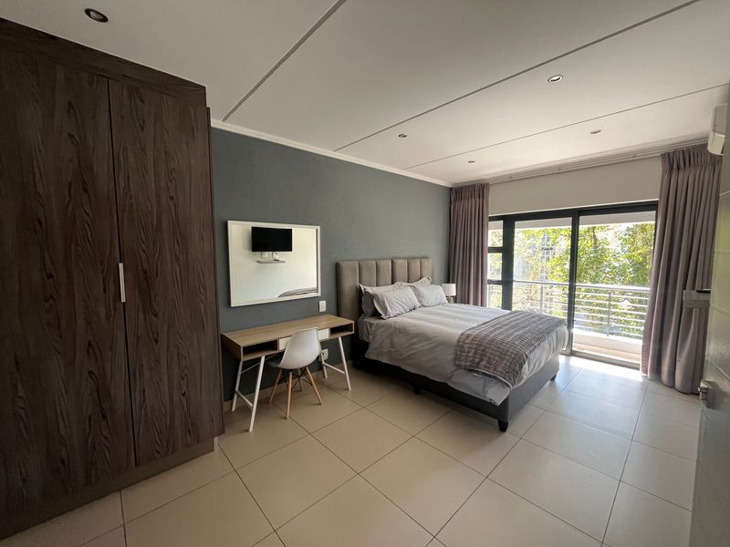 Spacious bedroom featuring tiled flooring, built-in wardrobe, and sliding glass doors leading to a private balcony with natural light.