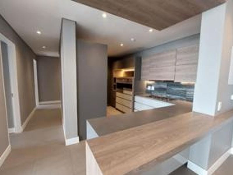 Modern kitchen featuring sleek built-in cabinetry, stone countertops, a breakfast bar, and integrated hob, finished with contemporary recessed lighting and tiled flooring.
