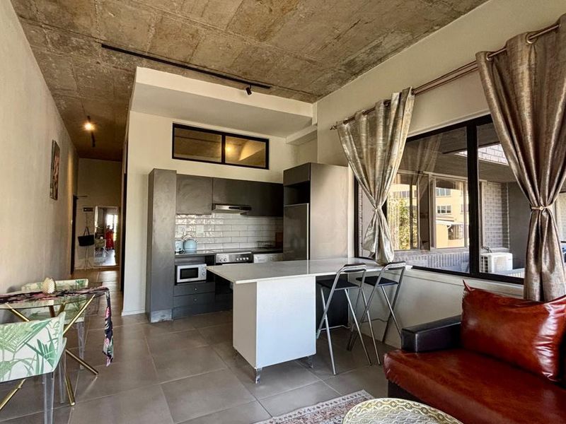 Modern open-plan living area featuring an exposed concrete ceiling, sleek kitchen cabinetry with subway tile backsplash, and a functional kitchen island.