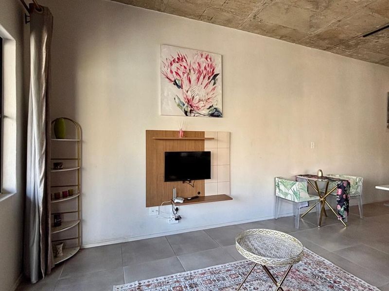Open-plan living area featuring modern tiled floors, an exposed concrete ceiling, and a built-in media console, creating a contemporary industrial aesthetic.
