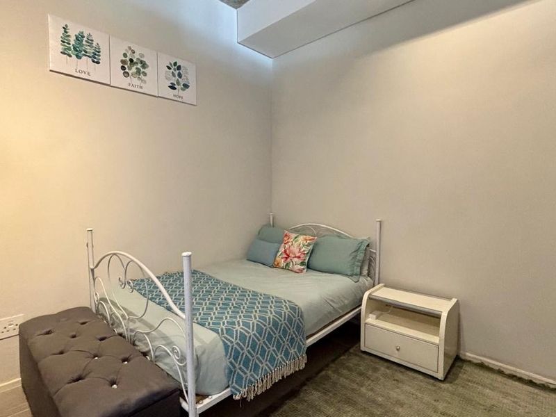 A compact bedroom featuring neutral walls and a built-in wardrobe, offering a functional space for rest.