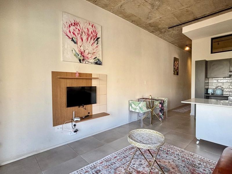 Modern open-plan living area featuring an exposed concrete ceiling, tiled floors, and a sleek kitchen with a central island and subway tile backsplash.