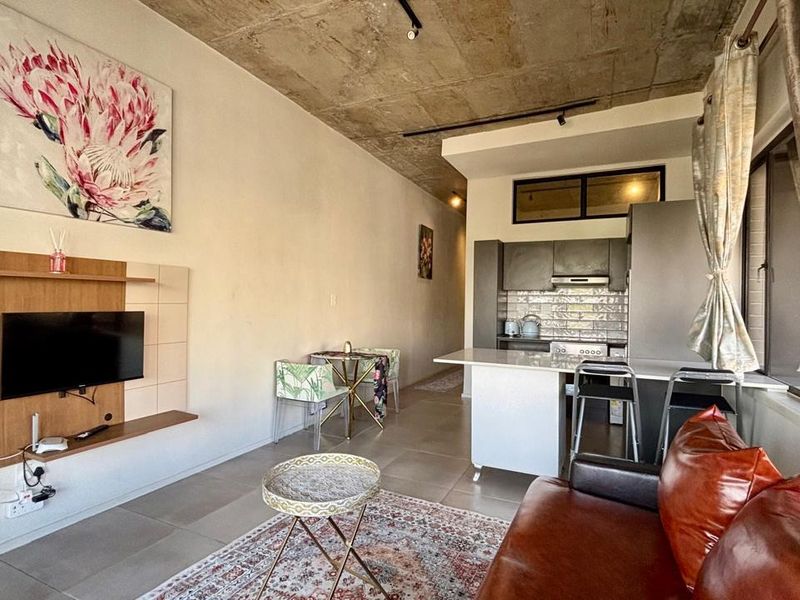 Modern open-plan living area featuring an exposed concrete ceiling, a sleek kitchen with an island, and a built-in media unit.