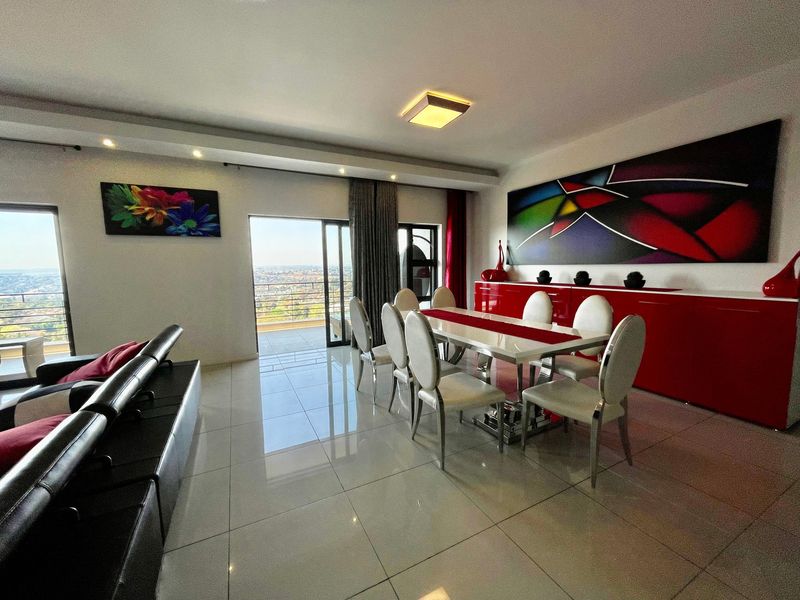 Spacious open-plan living and dining area featuring polished tile flooring, recessed lighting, and large sliding doors leading to a balcony with expansive views.
