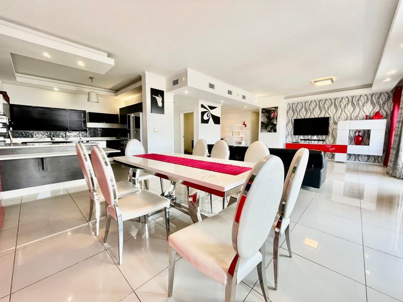 Spacious open-plan living and dining area featuring polished porcelain tiles, modern kitchen cabinetry, and integrated ceiling lighting with a contemporary aesthetic.